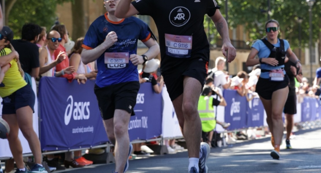 A picture of myself (Luc Shelton) running the final stretch of the ASICS London 10K. I am running alongside someone who is waving.